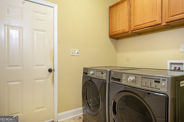 washroom featuring cabinets and washer and clothes dryer