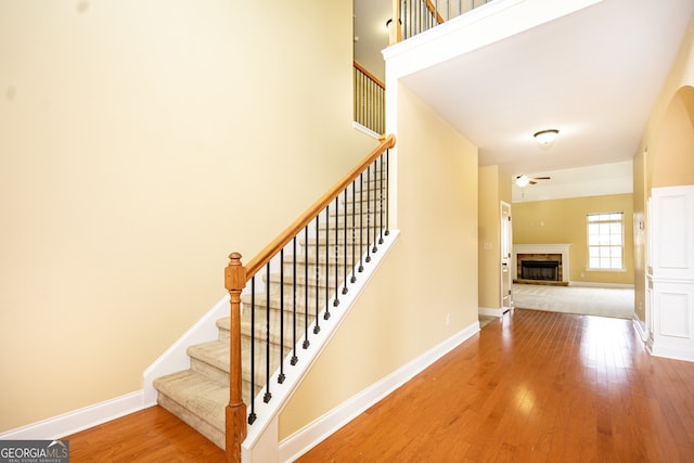 stairway with a tiled fireplace and wood-type flooring