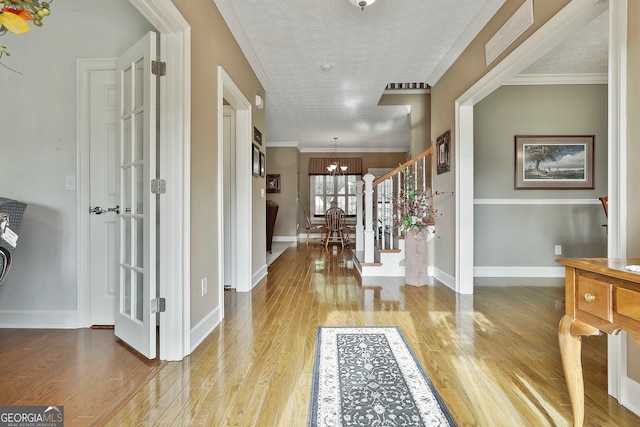 entrance foyer with wood-type flooring, a chandelier, and crown molding