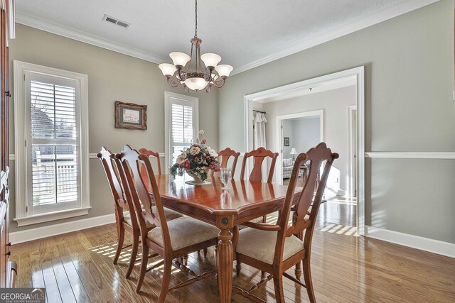 dining space with an inviting chandelier, light wood-type flooring, and crown molding