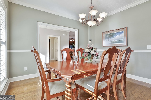 dining area featuring a chandelier, baseboards, light wood finished floors, and ornamental molding