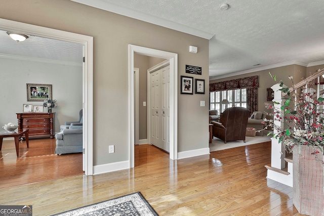 foyer with wood-type flooring, ornamental molding, and a textured ceiling