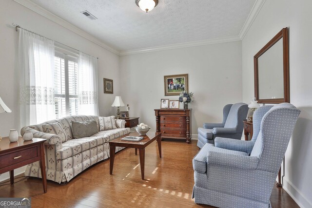 living room with hardwood / wood-style floors, crown molding, and a textured ceiling