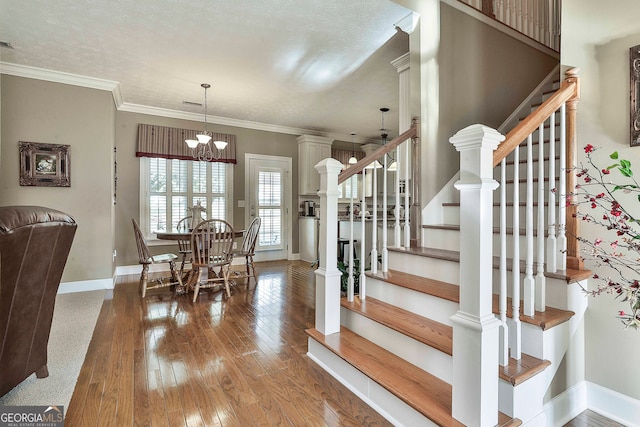 interior space featuring hardwood / wood-style flooring, a textured ceiling, an inviting chandelier, and ornamental molding