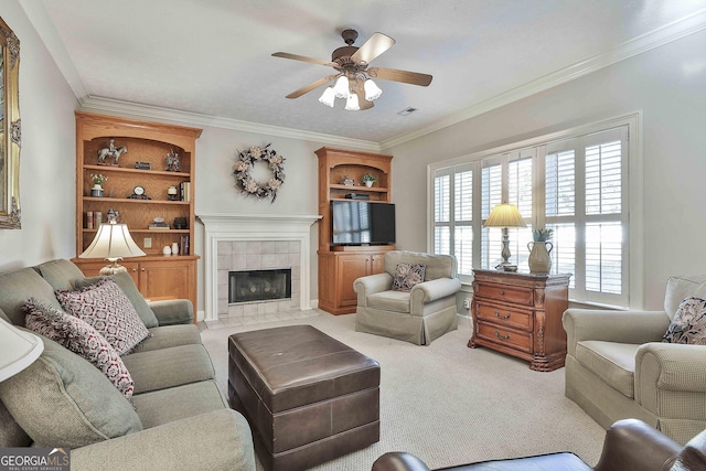 carpeted living room with ceiling fan, crown molding, and a tile fireplace