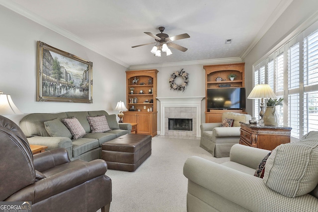 living area featuring a tiled fireplace, visible vents, ornamental molding, and carpet floors