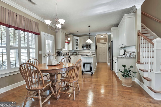 dining area featuring hardwood / wood-style floors, a textured ceiling, an inviting chandelier, and crown molding