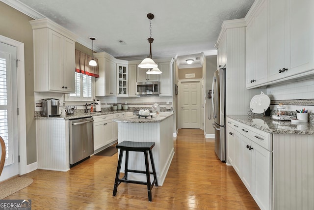 kitchen featuring pendant lighting, light wood-type flooring, stainless steel appliances, and a center island