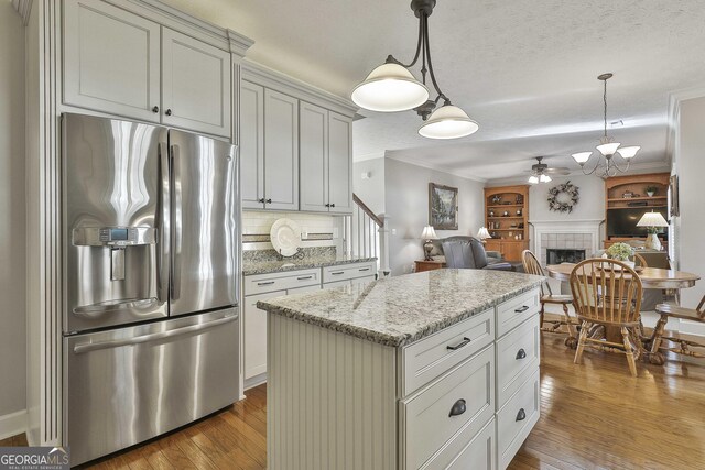 kitchen featuring a center island, stainless steel appliances, white cabinetry, hanging light fixtures, and light hardwood / wood-style flooring