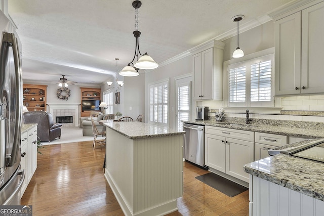 kitchen with a fireplace, decorative backsplash, hardwood / wood-style flooring, appliances with stainless steel finishes, and open floor plan