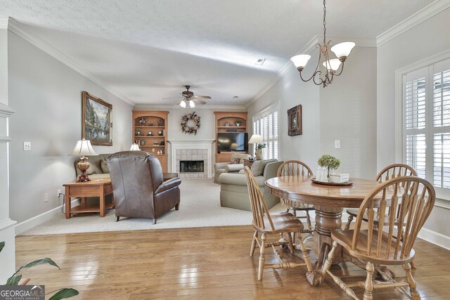 kitchen featuring stainless steel appliances, hanging light fixtures, light stone countertops, a fireplace, and light wood-type flooring