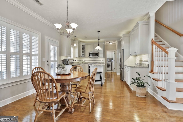 dining space with baseboards, stairway, light wood-type flooring, an inviting chandelier, and washer / clothes dryer