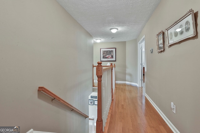 hall featuring a textured ceiling and light hardwood / wood-style floors