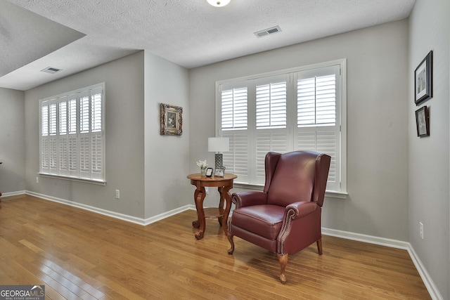 living area featuring visible vents, baseboards, and wood finished floors