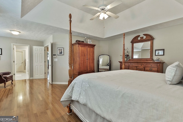 bedroom with ceiling fan, a textured ceiling, and light hardwood / wood-style flooring