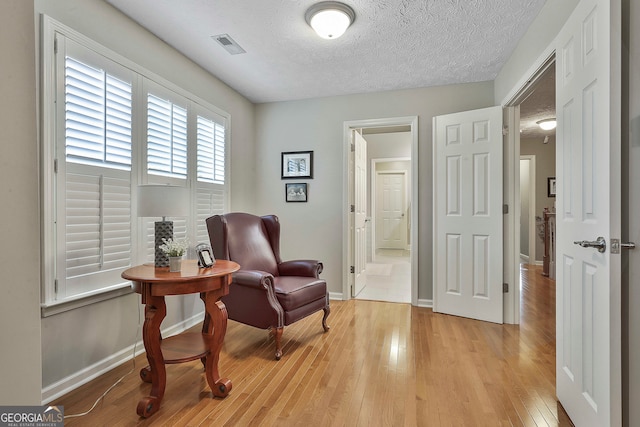 sitting room with light wood-type flooring and a textured ceiling