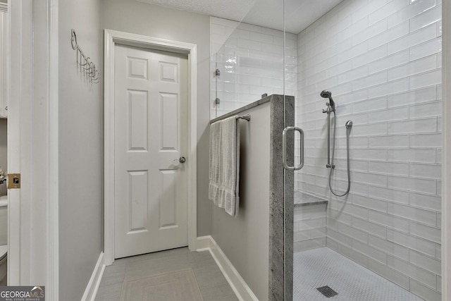 bathroom featuring tile patterned floors, baseboards, and a stall shower