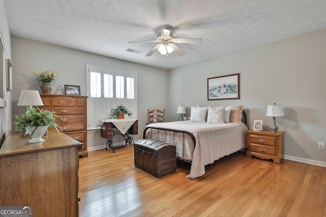 bedroom featuring a textured ceiling, ceiling fan, and light hardwood / wood-style flooring