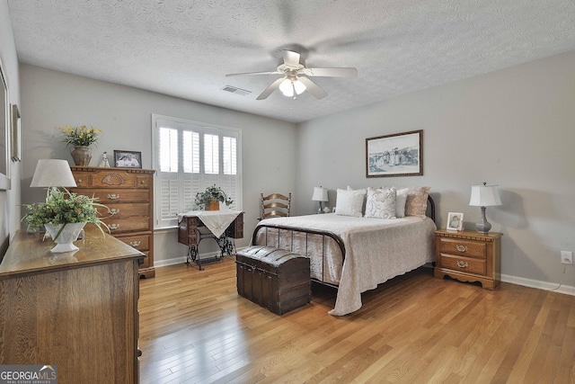 bedroom with visible vents, ceiling fan, baseboards, light wood-type flooring, and a textured ceiling