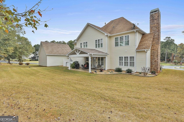 back of house with a lawn, a chimney, a patio, and roof with shingles