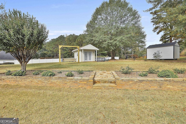 view of yard with french doors, an outdoor structure, and fence