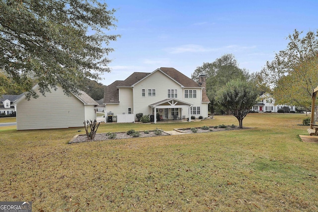 rear view of property featuring a lawn and a chimney