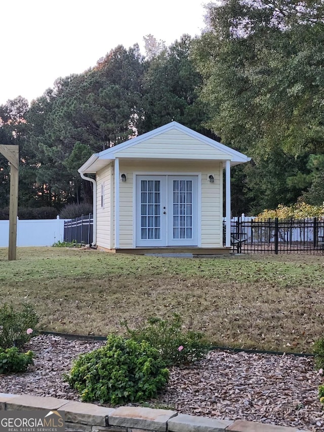 view of outdoor structure with french doors, an outdoor structure, and fence