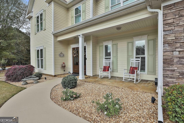 property entrance with a porch and stone siding