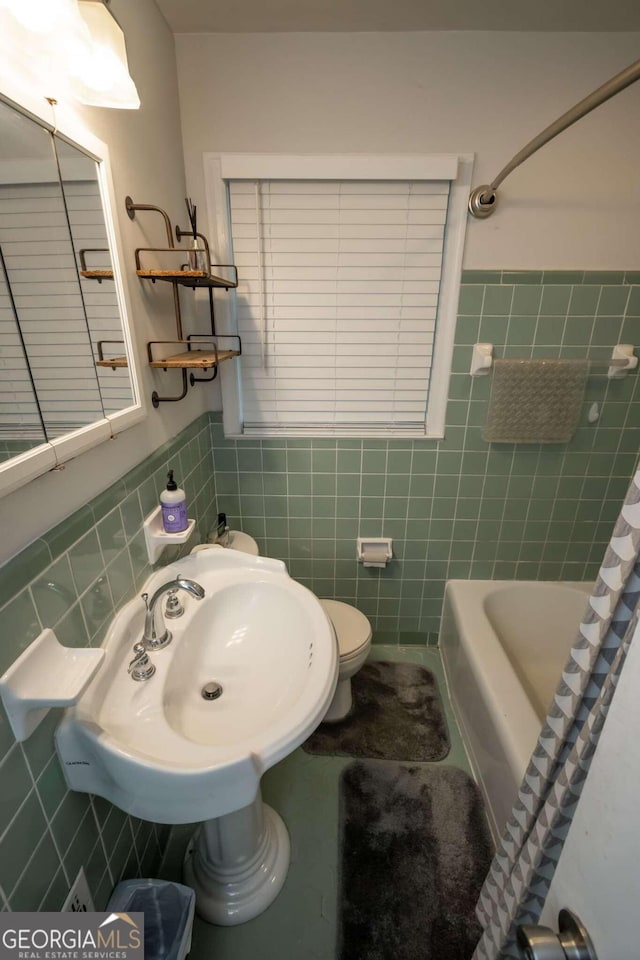 full bathroom featuring tile walls, shower / bath combo, sink, and toilet