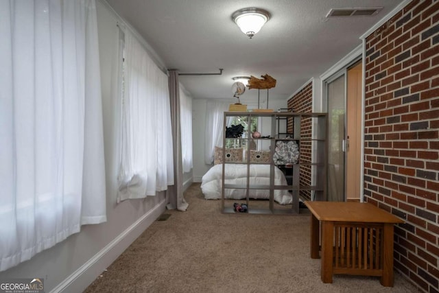 bedroom featuring a textured ceiling, brick wall, light carpet, and crown molding