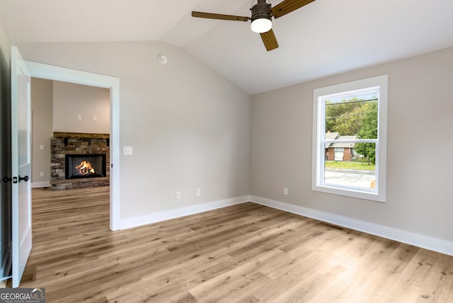 spare room with light wood-type flooring, lofted ceiling, ceiling fan, and a fireplace