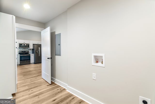 clothes washing area featuring electric panel, light hardwood / wood-style floors, and washer hookup