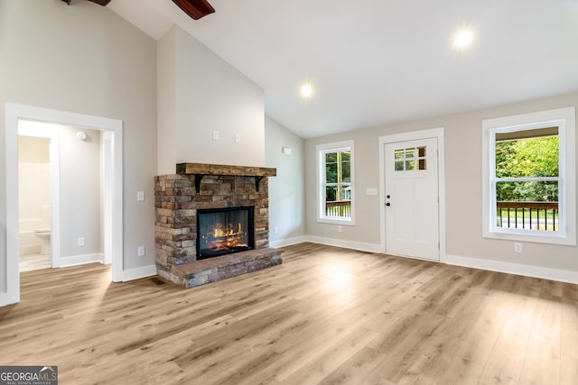 unfurnished living room featuring a fireplace, a wealth of natural light, light wood-type flooring, and high vaulted ceiling