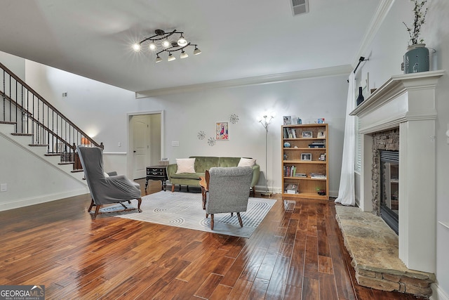 living room with ornamental molding, hardwood / wood-style flooring, and a stone fireplace