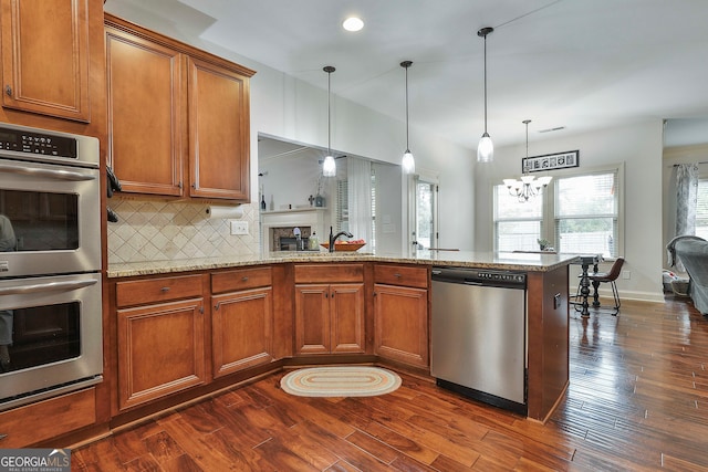 kitchen with dark hardwood / wood-style flooring, a chandelier, decorative light fixtures, and stainless steel appliances