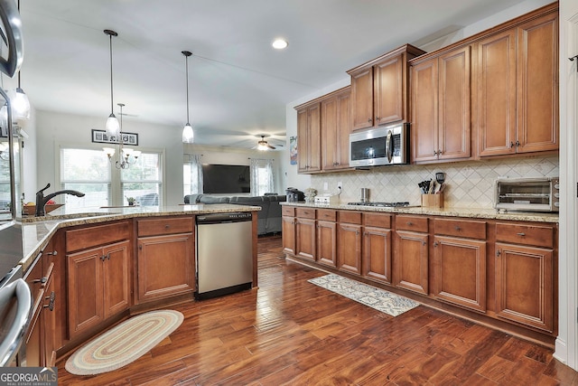 kitchen featuring hanging light fixtures, ceiling fan with notable chandelier, stainless steel appliances, and dark wood-type flooring