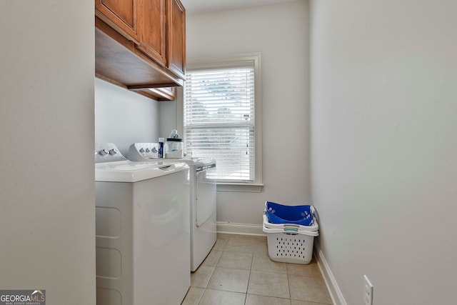 clothes washing area featuring washer and clothes dryer, cabinets, and light tile patterned floors