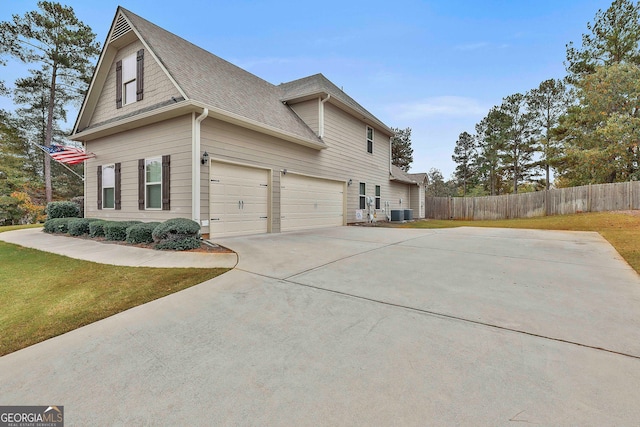 view of side of home featuring a garage, cooling unit, and a yard