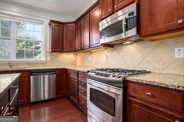 kitchen featuring dark hardwood / wood-style flooring, light stone countertops, and stainless steel appliances