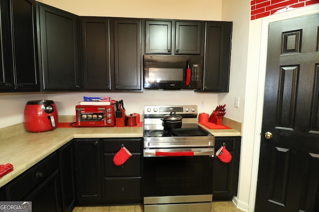 kitchen featuring light tile patterned floors and stainless steel electric range oven