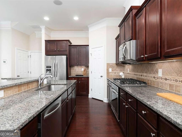 kitchen with stainless steel appliances, sink, light stone counters, ornamental molding, and dark hardwood / wood-style floors