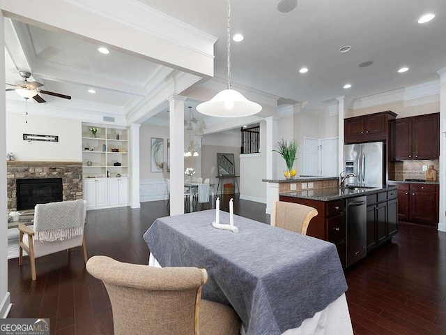 dining space with ornamental molding, dark hardwood / wood-style flooring, ceiling fan, and a stone fireplace