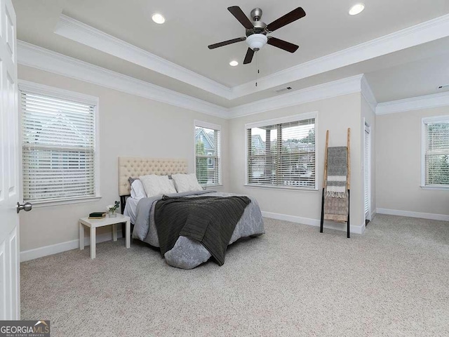 carpeted bedroom featuring multiple windows, a raised ceiling, ceiling fan, and crown molding