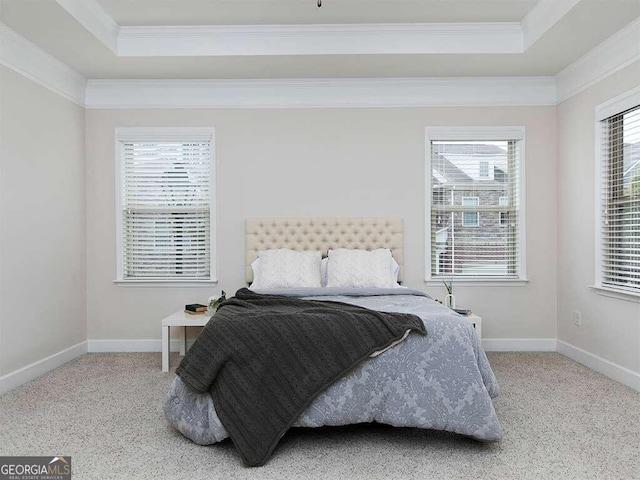 carpeted bedroom with a tray ceiling and ornamental molding