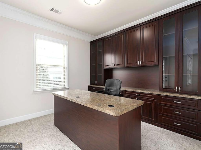 home office with built in desk, light colored carpet, and ornamental molding