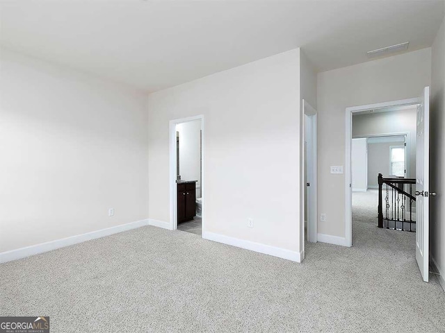 unfurnished bedroom with ensuite bath and light carpet