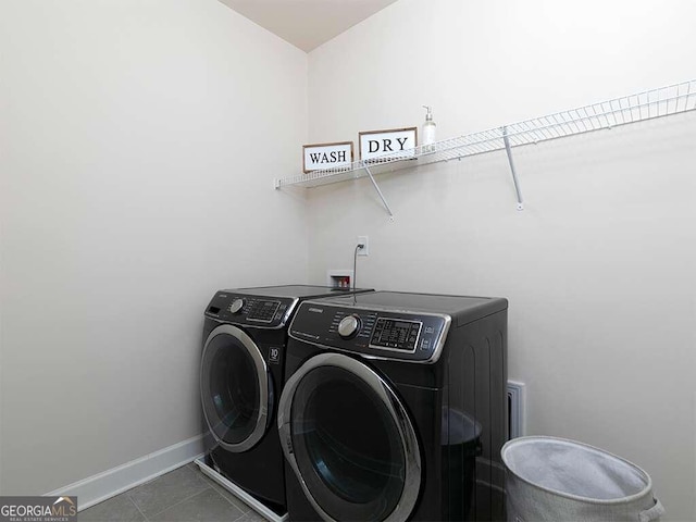 laundry area featuring washing machine and dryer and dark tile patterned floors