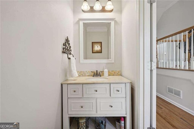 bathroom with crown molding, vanity, and hardwood / wood-style flooring