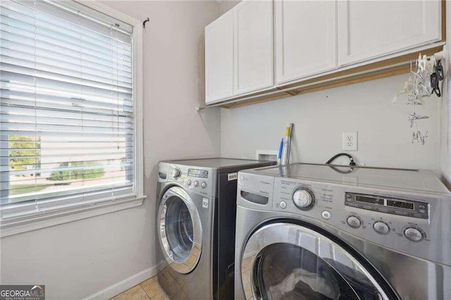 clothes washing area with washer and clothes dryer, light tile patterned flooring, and cabinets