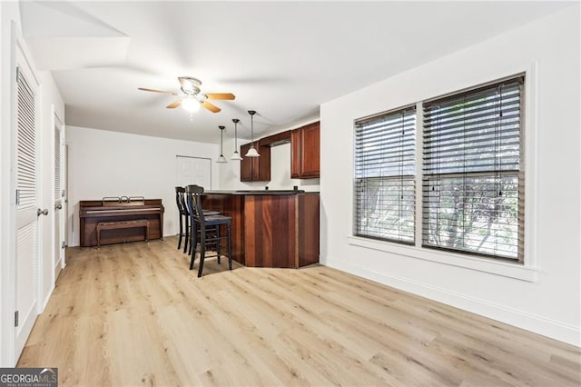 kitchen featuring pendant lighting, light wood-type flooring, ceiling fan, and a breakfast bar area